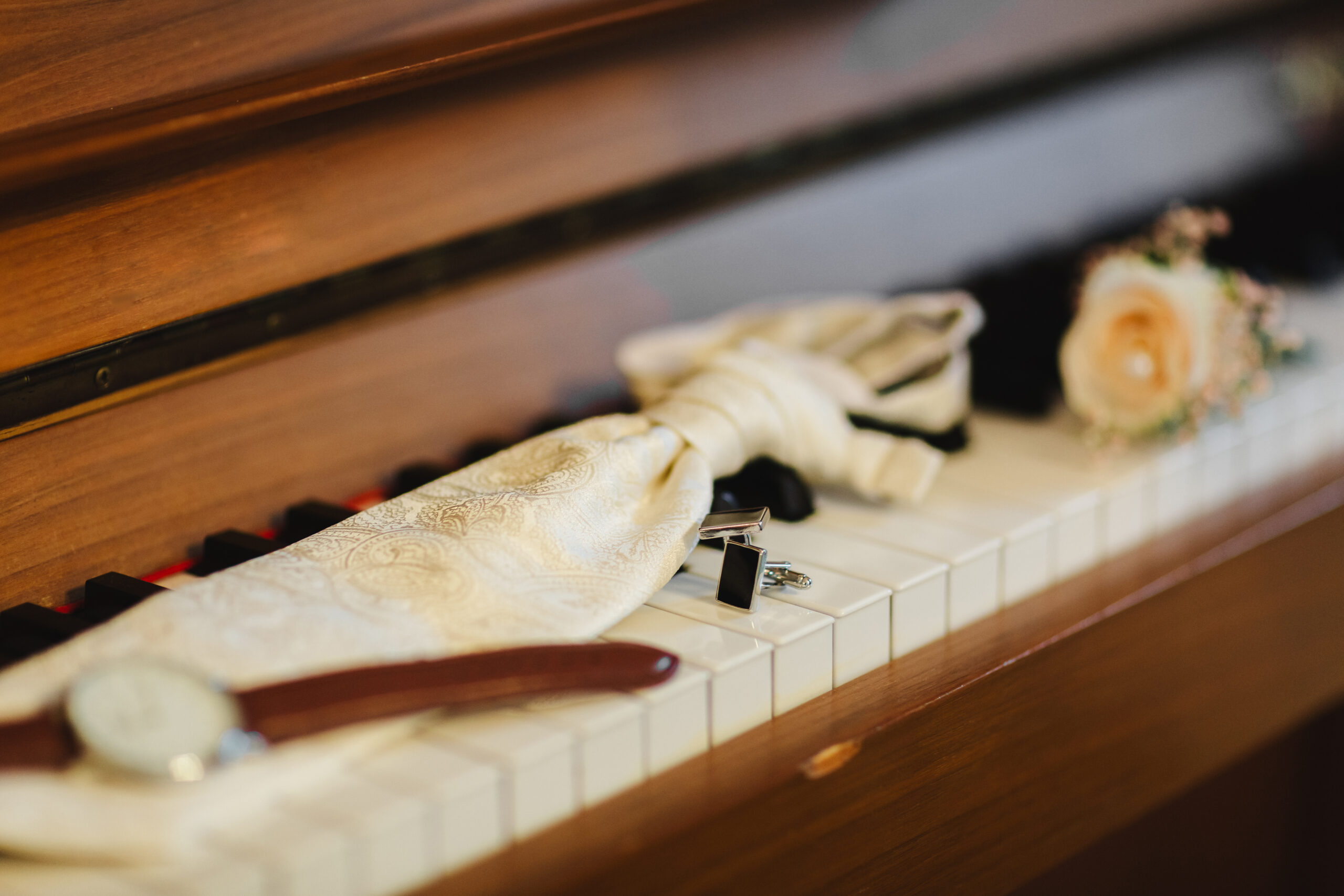 Accessoires du marié. Montre élégante, cravate, boutonnière et boutons de manchette sur les touches du piano. Le matin du marié.